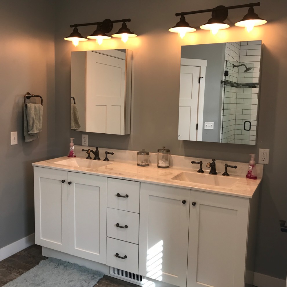Design ideas for a mid-sized country master bathroom in Grand Rapids with shaker cabinets, white cabinets, marble benchtops, brown floor, a hinged shower door, white benchtops, a freestanding tub, a double shower, white tile, subway tile, grey walls, porcelain floors and an undermount sink.