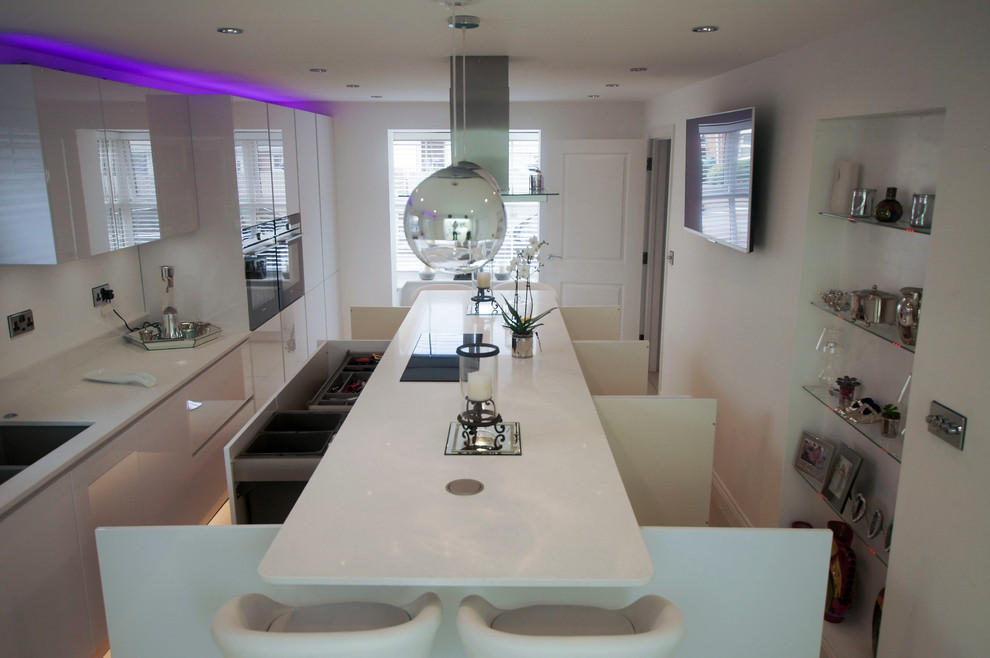 Inspiration for a large contemporary single-wall eat-in kitchen in Hertfordshire with a double-bowl sink, glass-front cabinets, white cabinets, quartzite benchtops, white splashback, ceramic splashback, panelled appliances, ceramic floors and with island.