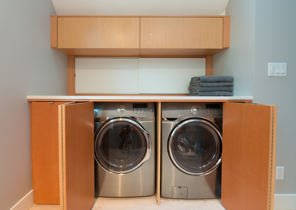 Inspiration for a contemporary laundry cupboard in Vancouver with flat-panel cabinets, medium wood cabinets and a side-by-side washer and dryer.