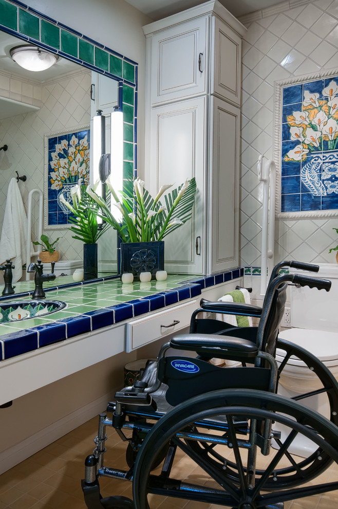 Photo of a small traditional master bathroom in San Diego with raised-panel cabinets, white cabinets, a curbless shower, a two-piece toilet, green tile, terra-cotta tile, white walls, porcelain floors, an undermount sink and tile benchtops.