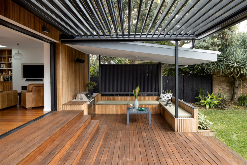 Mid-sized contemporary backyard and ground level deck in Sydney with a pergola.
