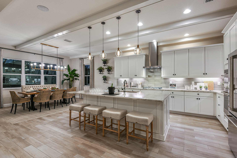This is an example of a transitional l-shaped kitchen in Columbus with an undermount sink, shaker cabinets, white cabinets, stainless steel appliances, with island, beige floor and grey benchtop.