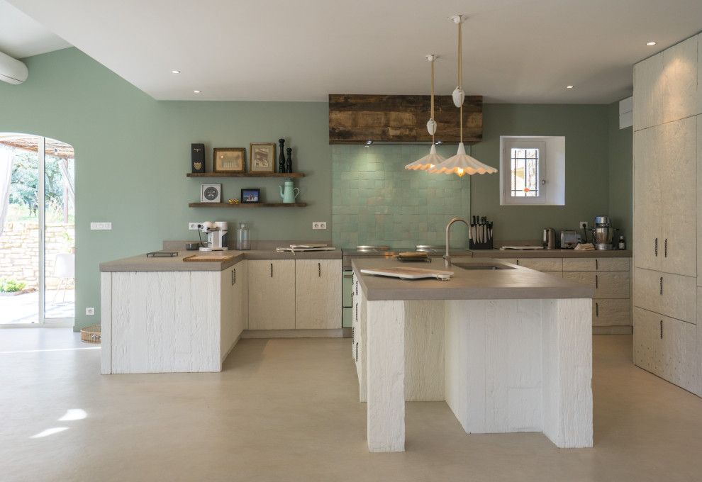 This is an example of a mid-sized country u-shaped eat-in kitchen in Other with an undermount sink, beaded inset cabinets, white cabinets, concrete benchtops, green splashback, ceramic splashback, coloured appliances, concrete floors, multiple islands, grey floor and grey benchtop.