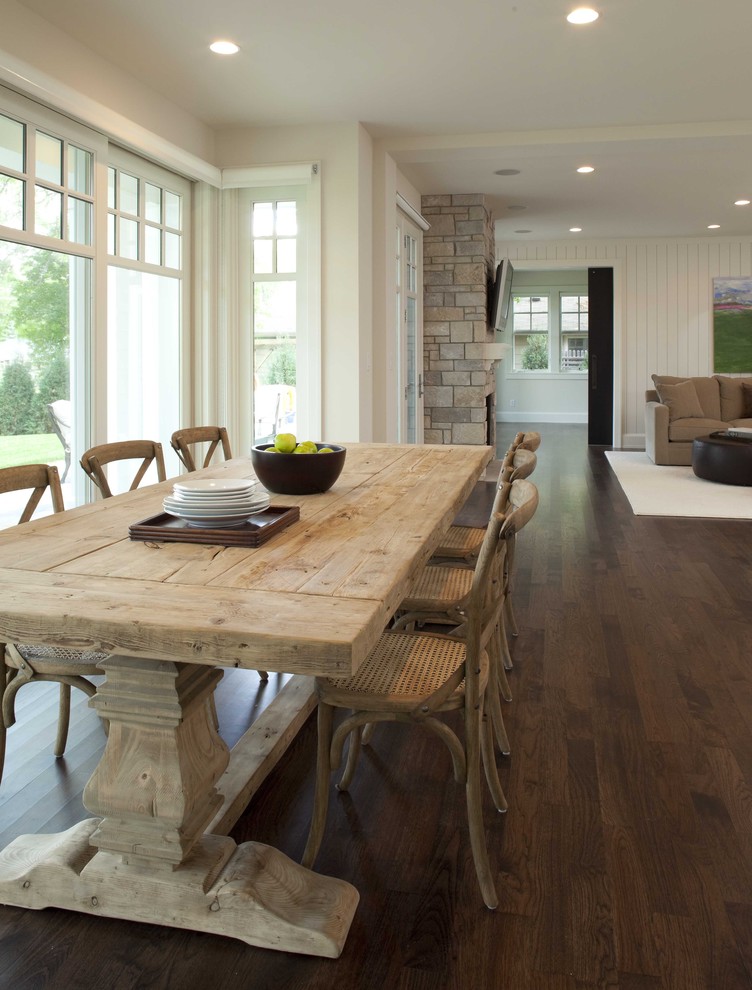 This is an example of a country open plan dining in Minneapolis with white walls, dark hardwood floors and brown floor.