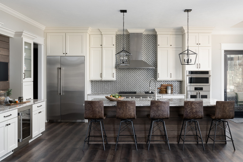 Example of a mid-sized beach style l-shaped dark wood floor eat-in kitchen design in Indianapolis with an undermount sink, shaker cabinets, white cabinets, granite countertops, subway tile backsplash, stainless steel appliances and an island