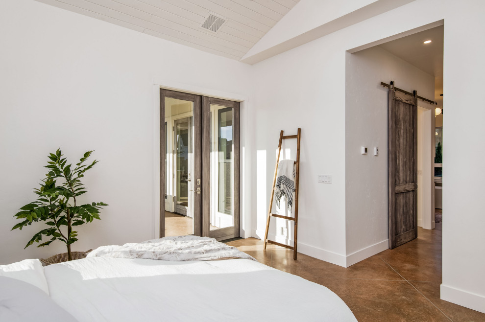 This is an example of a large master bedroom in Portland with white walls, concrete flooring and brown floors.