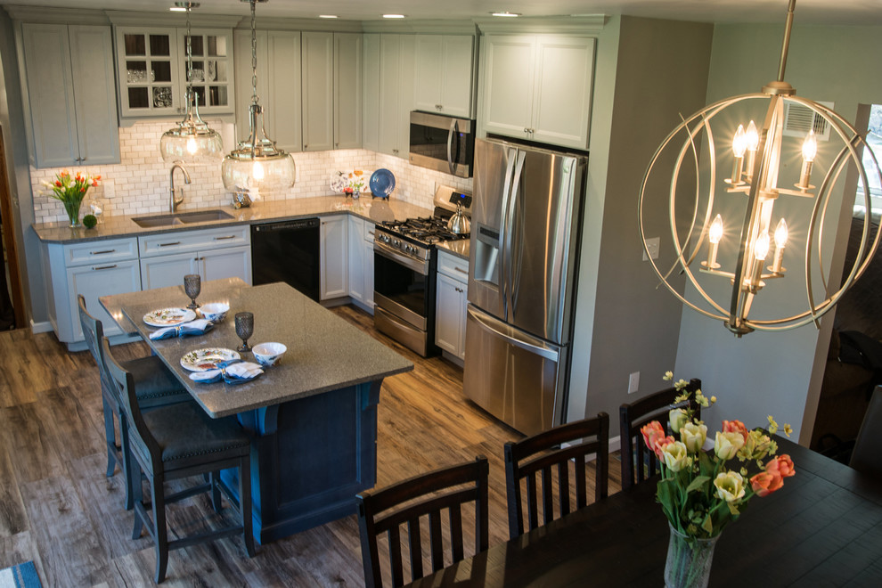 Eat-in kitchen - mid-sized transitional l-shaped vinyl floor eat-in kitchen idea with an undermount sink, recessed-panel cabinets, gray cabinets, quartz countertops, white backsplash, marble backsplash, stainless steel appliances and an island