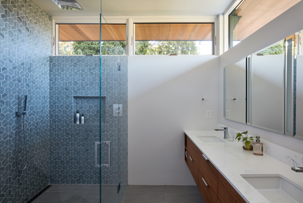 Modernes Badezimmer mit flächenbündigen Schrankfronten, hellbraunen Holzschränken, bodengleicher Dusche, blauen Fliesen, weißer Wandfarbe, Unterbauwaschbecken, grauem Boden, Falttür-Duschabtrennung, weißer Waschtischplatte, Doppelwaschbecken und schwebendem Waschtisch in San Francisco