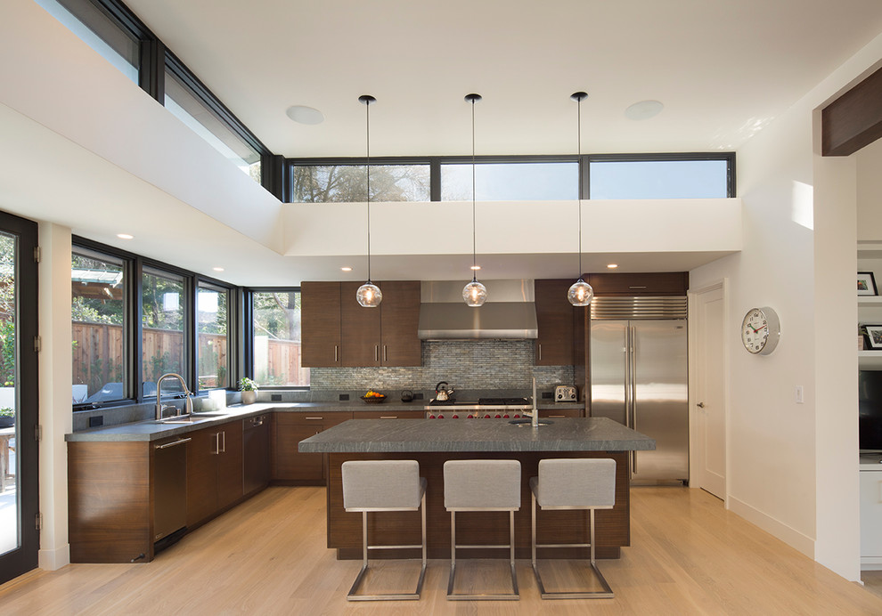 Design ideas for a large contemporary l-shaped separate kitchen in San Francisco with an undermount sink, flat-panel cabinets, dark wood cabinets, grey splashback, metal splashback, stainless steel appliances, with island, soapstone benchtops, light hardwood floors and grey benchtop.