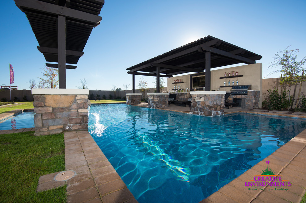 Huge minimalist backyard brick pool photo in Phoenix with a pergola