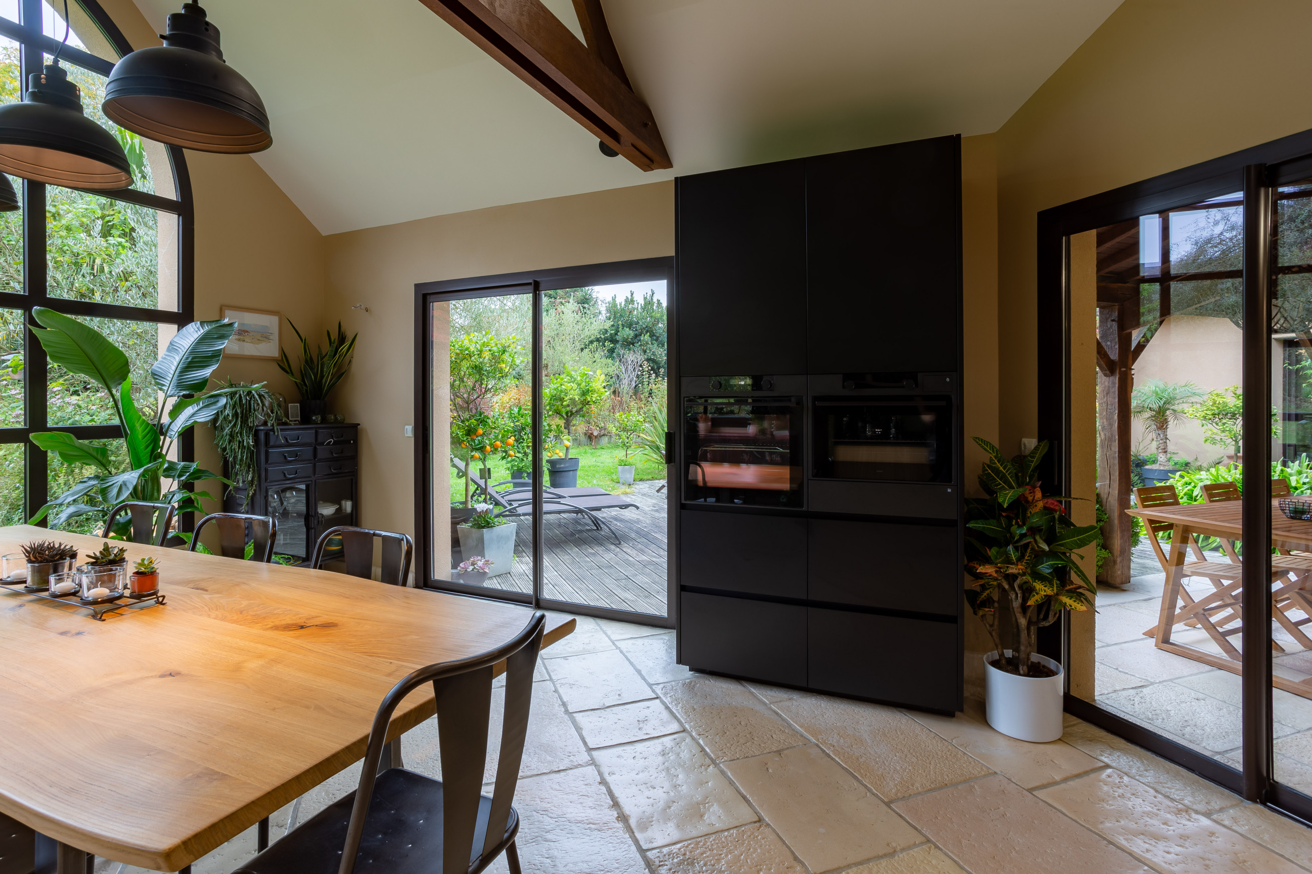 Réalisation d'une cuisine noire et bois dans un écrin végétal
