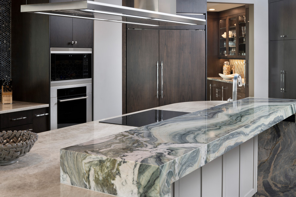 This is an example of a large contemporary single-wall open plan kitchen in Miami with an undermount sink, flat-panel cabinets, dark wood cabinets, quartzite benchtops, multi-coloured splashback, porcelain splashback, stainless steel appliances, porcelain floors, with island, beige floor, multi-coloured benchtop and recessed.