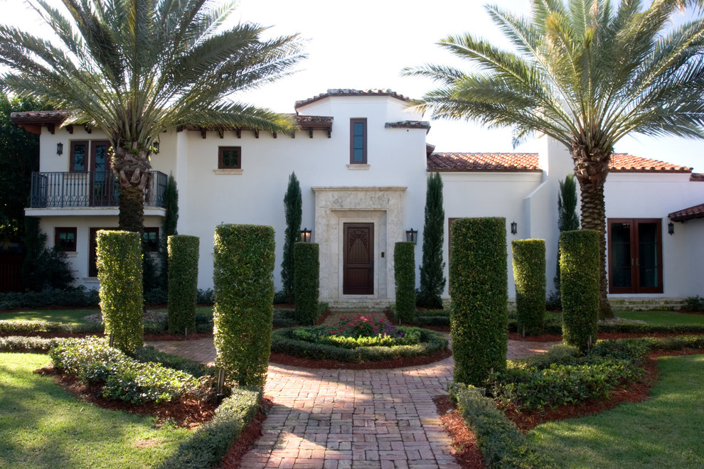 Inspiration for a large mediterranean front yard partial sun formal garden for spring in Miami with brick pavers and a garden path.