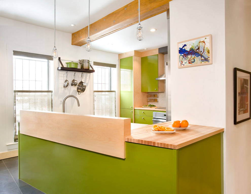 Small industrial u-shaped eat-in kitchen in Boston with a farmhouse sink, flat-panel cabinets, green cabinets, wood benchtops, white splashback, stone tile splashback, stainless steel appliances, slate floors and a peninsula.