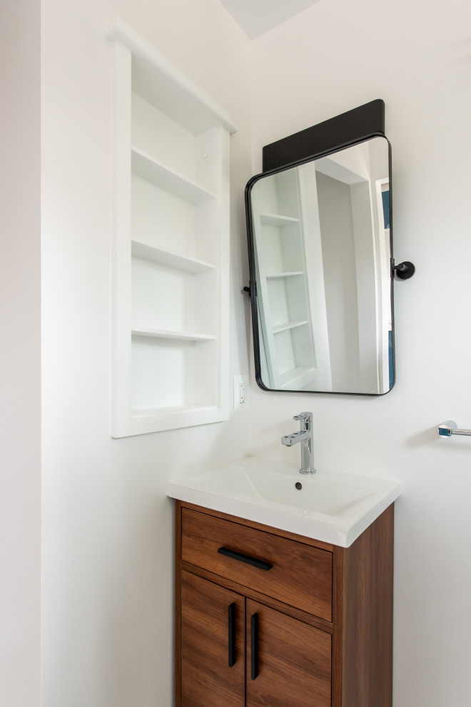 This is an example of a small contemporary 3/4 bathroom in DC Metro with furniture-like cabinets, medium wood cabinets, a corner shower, a one-piece toilet, white tile, subway tile, white walls, linoleum floors, a console sink, grey floor, a hinged shower door, a laundry, a single vanity and a built-in vanity.