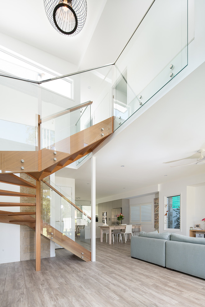 Design ideas for a small tropical wood u-shaped staircase in Sunshine Coast with glass railing.