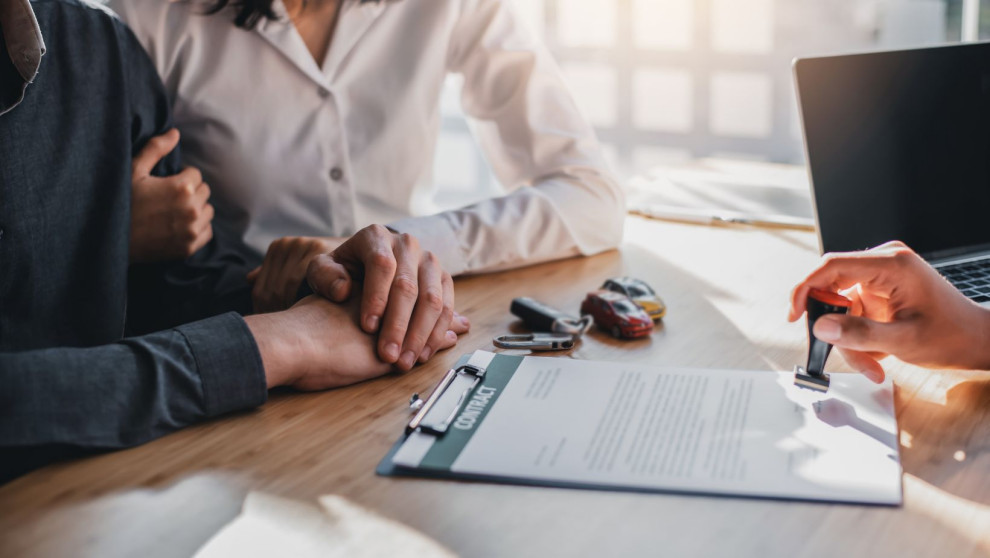two people across the desk from another who is stamping a document