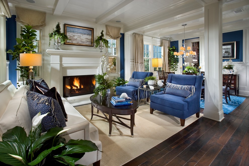 Design ideas for a mid-sized traditional formal open concept living room in Orange County with blue walls, dark hardwood floors, a standard fireplace, no tv, a plaster fireplace surround and brown floor.