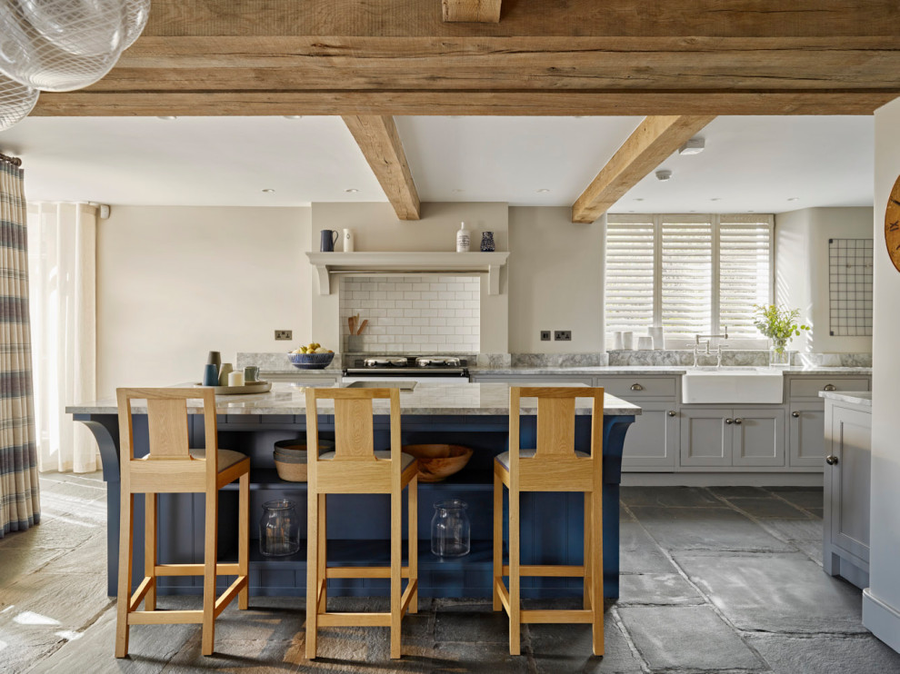 Inspiration for a large country eat-in kitchen in Other with a farmhouse sink, beaded inset cabinets, blue cabinets, white splashback, ceramic splashback, stainless steel appliances, with island, grey floor and grey benchtop.