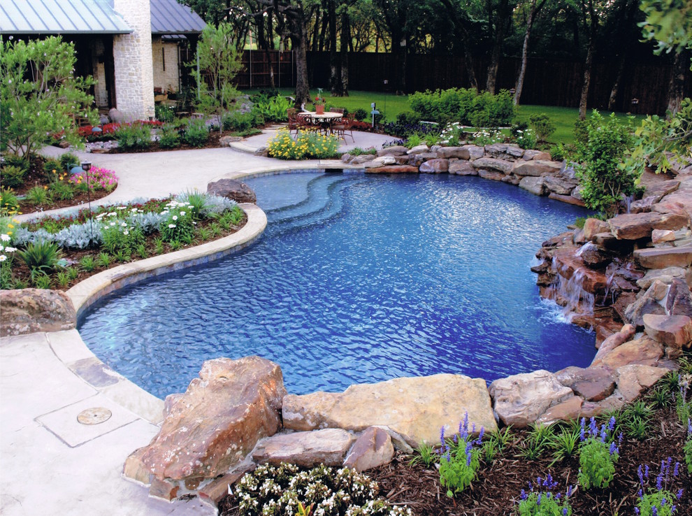 Photo of a mid-sized country backyard custom-shaped natural pool in Dallas with stamped concrete.