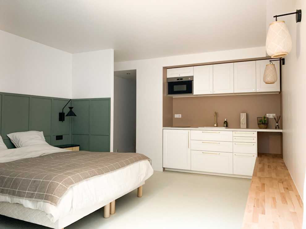 Esempio di una camera degli ospiti minimal di medie dimensioni con pareti verdi, pavimento in cemento, nessun camino, pavimento bianco e boiserie