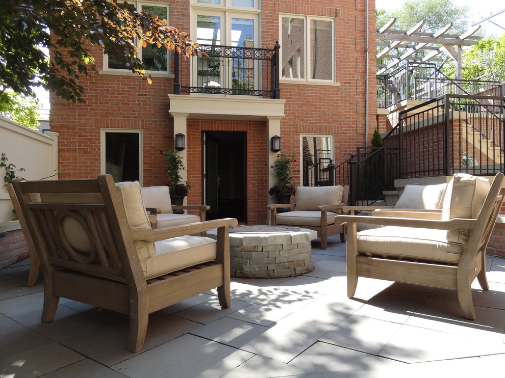 This is an example of a mid-sized transitional courtyard patio in Chicago with a fire feature, concrete pavers and no cover.