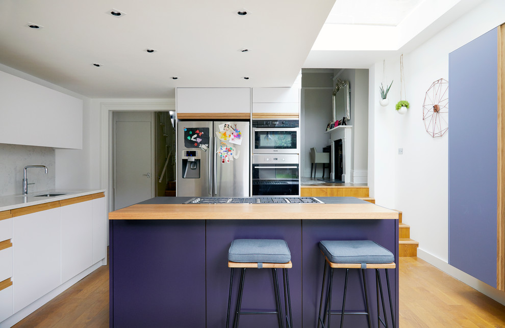 This is an example of a large contemporary l-shaped eat-in kitchen in London with an integrated sink, flat-panel cabinets, purple cabinets, solid surface benchtops, white splashback, stone slab splashback, stainless steel appliances, medium hardwood floors, with island and brown floor.