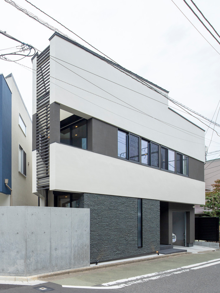 Photo of a mid-sized modern two-storey house exterior in Tokyo with a shed roof and a metal roof.