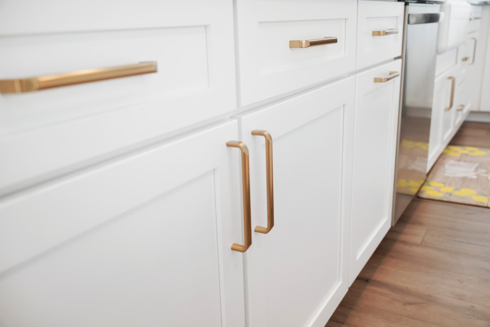 Large transitional l-shaped open concept kitchen photo in Denver with a farmhouse sink, shaker cabinets, white cabinets, quartz countertops, white backsplash, ceramic backsplash, stainless steel appliances, an island and gray countertops