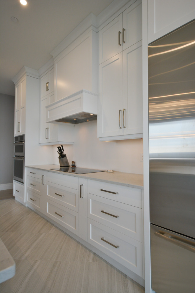 Inspiration for a mid-sized transitional open concept kitchen remodel in Toronto with shaker cabinets, white cabinets, quartz countertops, stainless steel appliances, a peninsula and white countertops