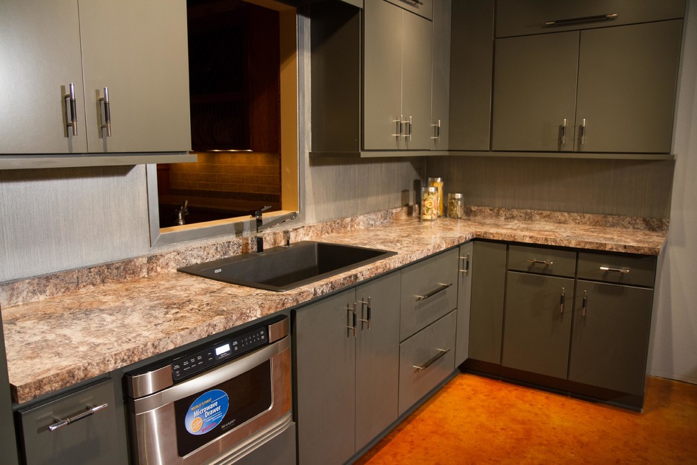 This is an example of a small contemporary l-shaped kitchen in Other with a single-bowl sink, flat-panel cabinets, grey cabinets, laminate benchtops, stainless steel appliances and concrete floors.