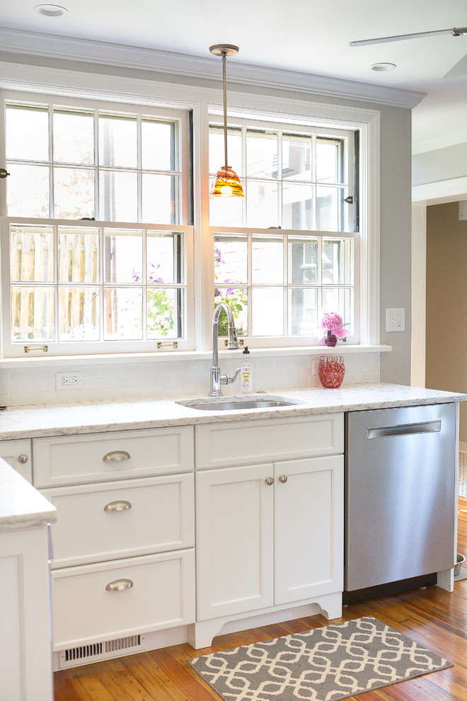 Inspiration for a small transitional light wood floor kitchen remodel with an undermount sink, shaker cabinets, white cabinets, quartz countertops, white backsplash, porcelain backsplash, stainless steel appliances and a peninsula