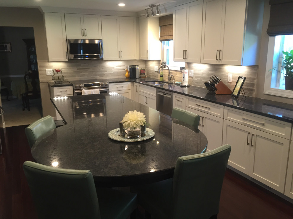 Photo of a large modern l-shaped kitchen/diner in DC Metro with shaker cabinets, white cabinets, granite worktops, grey splashback, stone tiled splashback, an island and grey worktops.