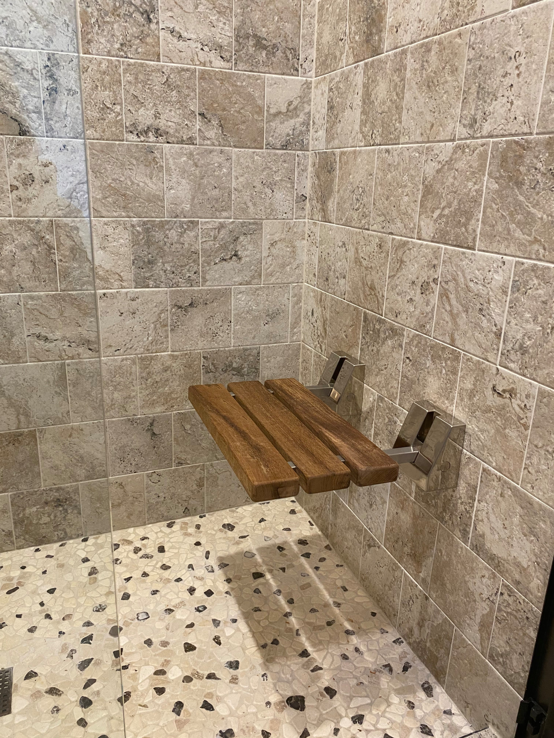 Teak wood foldable shower seat in custom tile shower