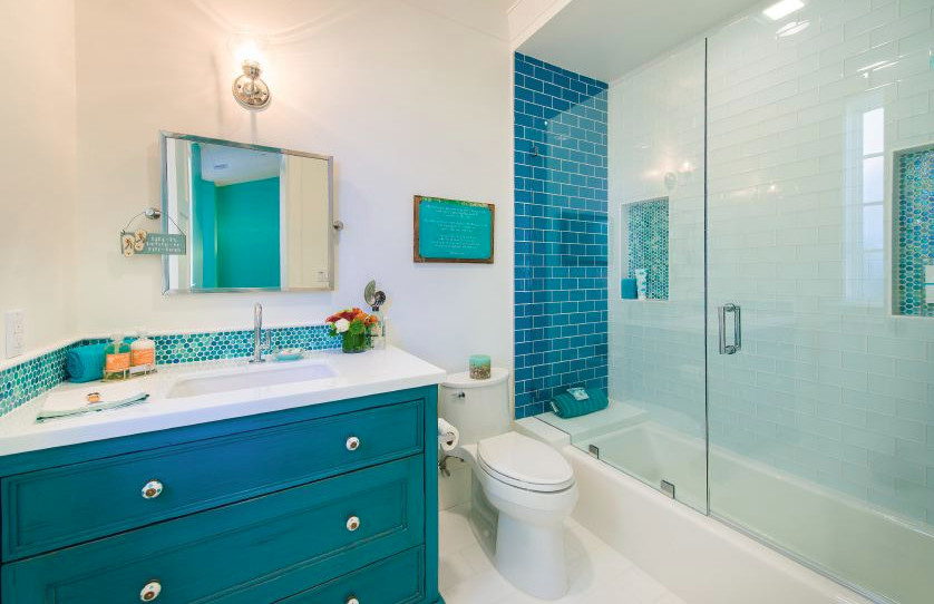 This is an example of a contemporary bathroom in Orange County with furniture-like cabinets, blue cabinets, an alcove tub, a one-piece toilet, blue tile, mosaic tile, white walls, ceramic floors, an undermount sink and engineered quartz benchtops.