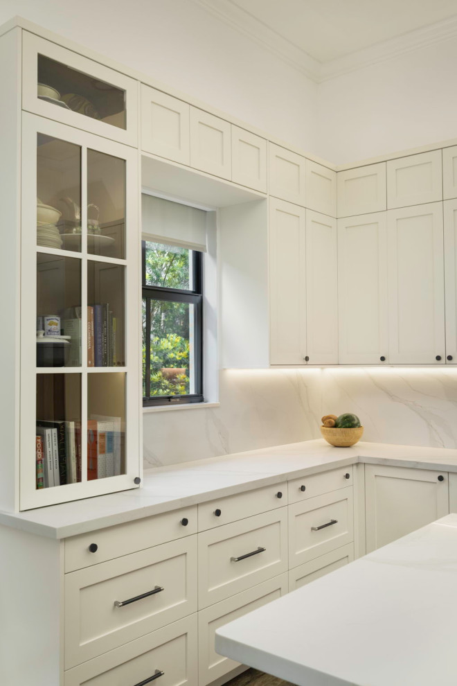 Example of a mid-sized transitional l-shaped laminate floor and brown floor eat-in kitchen design in Miami with a drop-in sink, shaker cabinets, medium tone wood cabinets, quartz countertops, white backsplash, quartz backsplash, stainless steel appliances, an island and white countertops