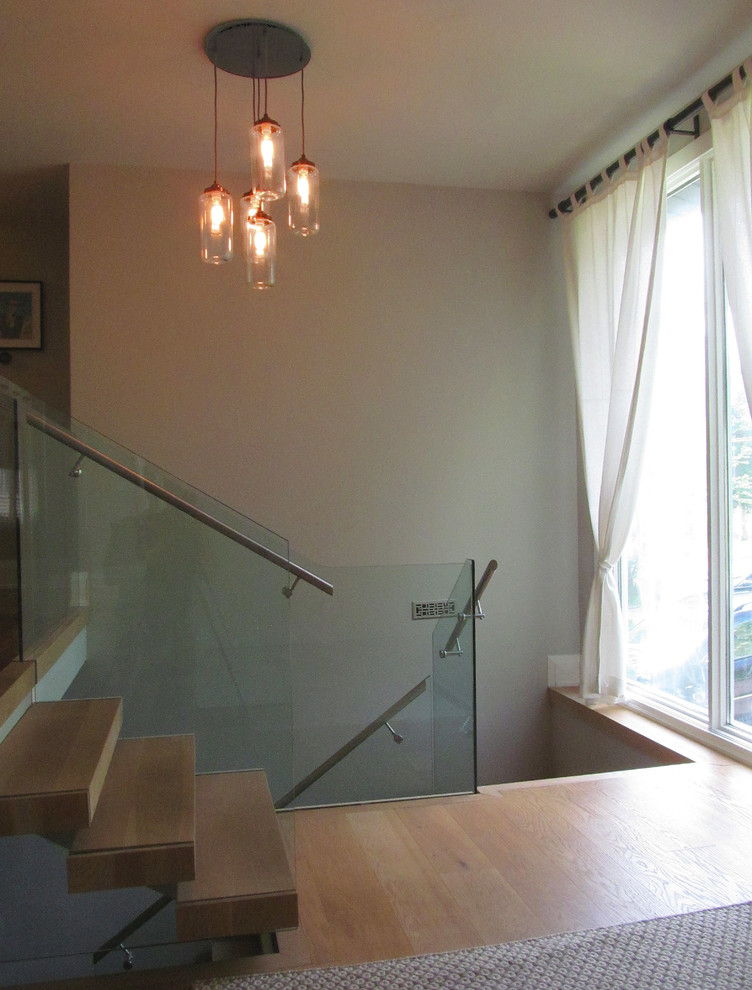 Photo of a mid-sized contemporary wood l-shaped staircase in Toronto with open risers and glass railing.