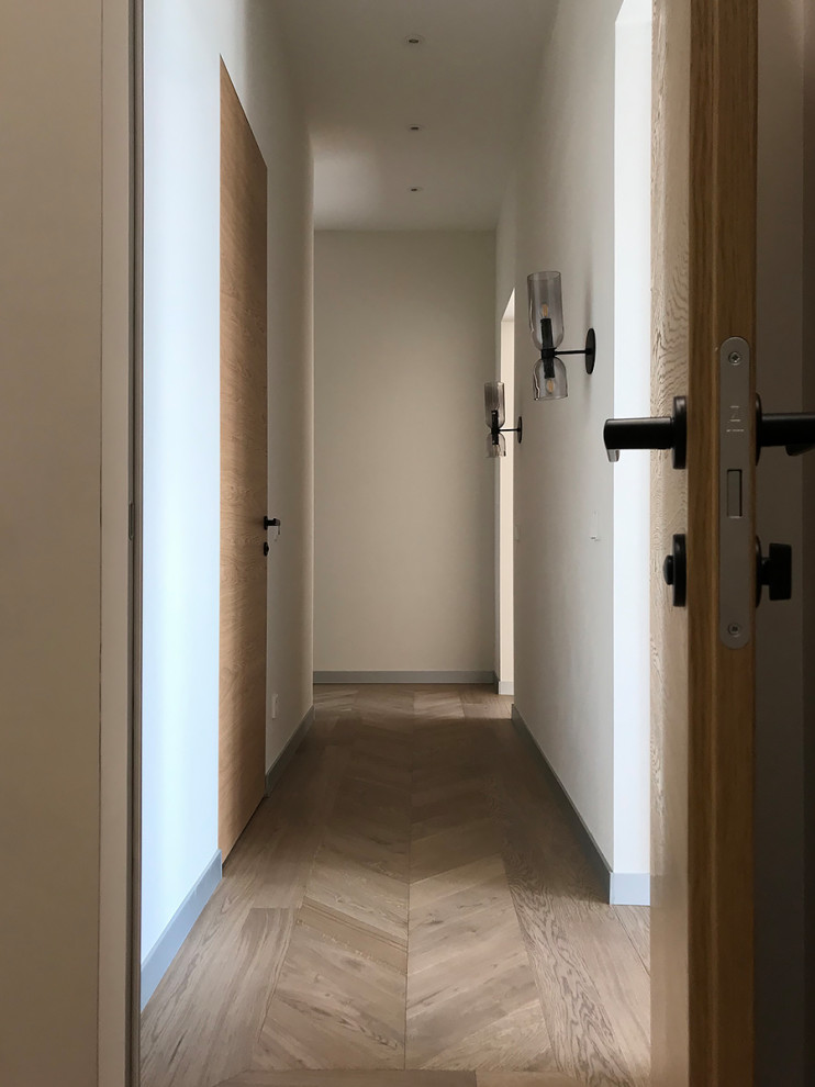 Пример оригинального дизайна: узкий коридор в современном стиле с белыми стенами и светлым паркетным полом