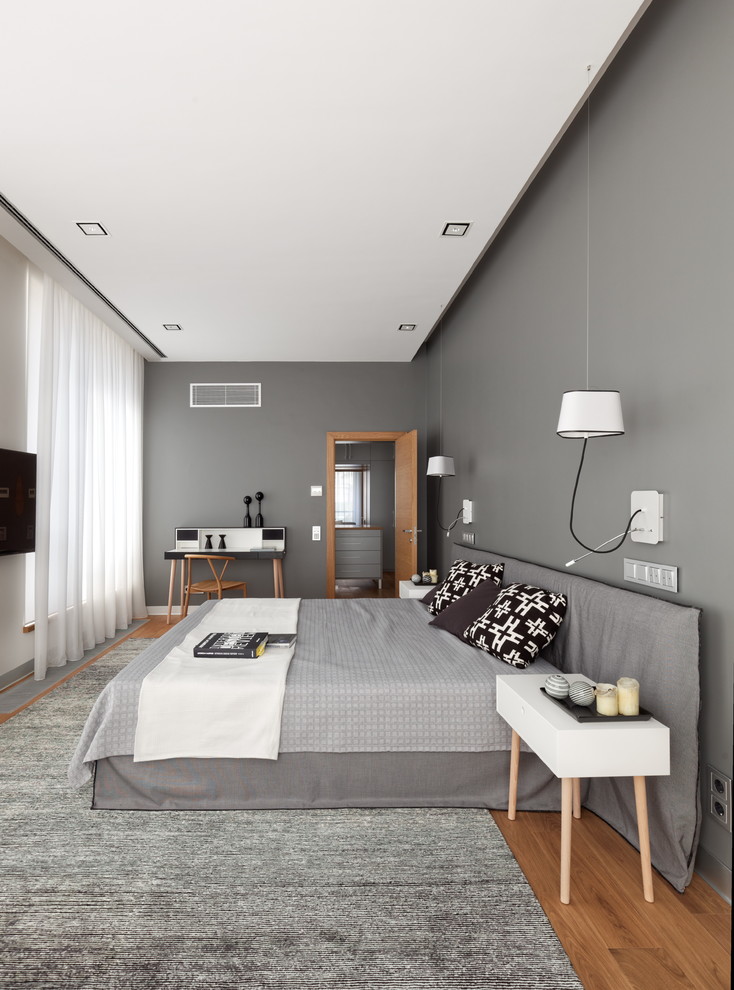 This is an example of a large contemporary master bedroom in Moscow with grey walls, medium hardwood floors, no fireplace and brown floor.