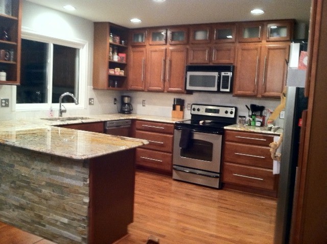 Eat-in kitchen - mid-sized transitional u-shaped light wood floor eat-in kitchen idea in Detroit with an undermount sink, flat-panel cabinets, medium tone wood cabinets, granite countertops, white backsplash, stone tile backsplash and stainless steel appliances