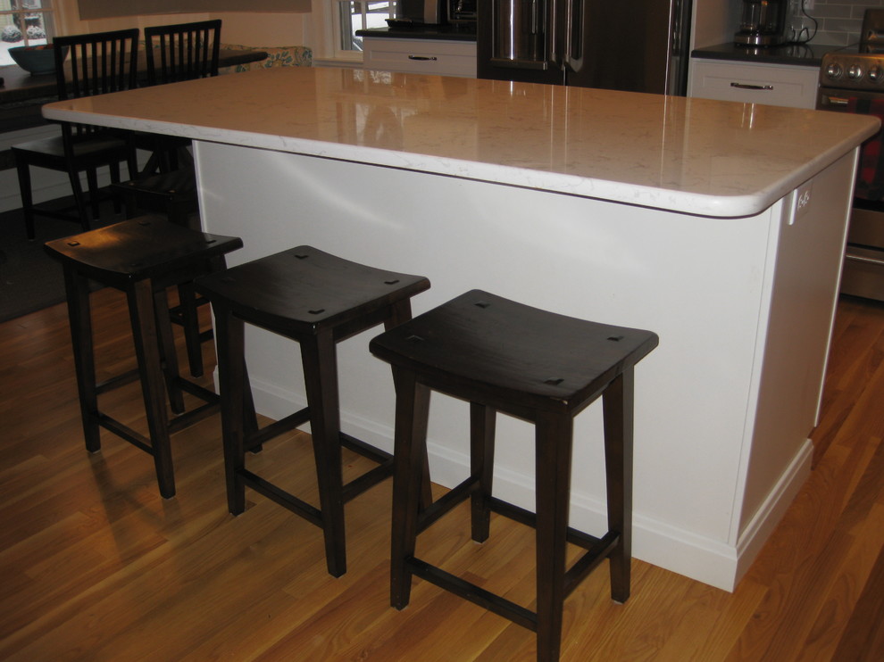 Transitional l-shaped medium tone wood floor eat-in kitchen photo in Boston with an undermount sink, white cabinets, quartz countertops, stainless steel appliances, an island, shaker cabinets, green backsplash, subway tile backsplash and black countertops