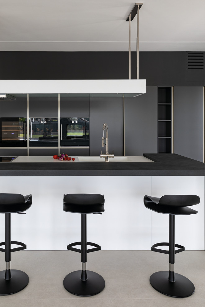 Inspiration för stora moderna svart kök, med en integrerad diskho, släta luckor, grå skåp, bänkskiva i koppar, grått stänkskydd, stänkskydd i keramik, rostfria vitvaror, cementgolv, en köksö och grått golv