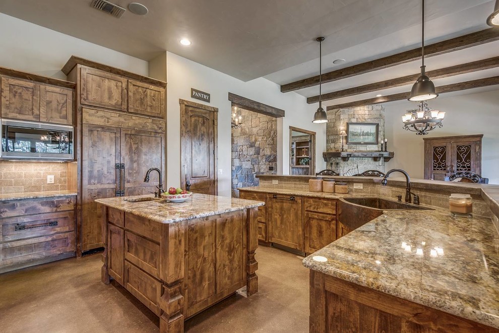 Example of a mid-sized mountain style l-shaped concrete floor and brown floor open concept kitchen design in Austin with a farmhouse sink, shaker cabinets, dark wood cabinets, granite countertops, gray backsplash, ceramic backsplash, stainless steel appliances, two islands and brown countertops