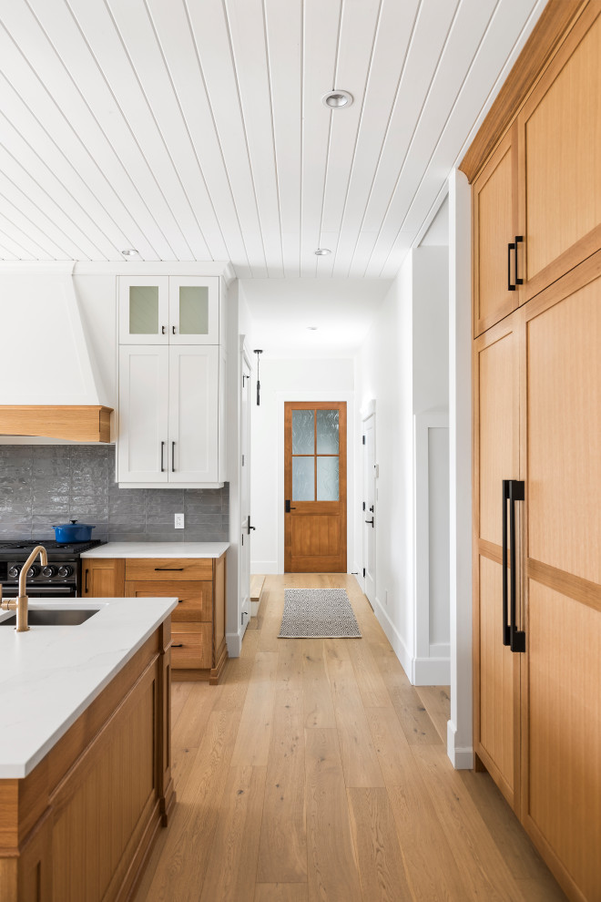 Inspiration for a small brown floor eat-in kitchen remodel with an undermount sink, shaker cabinets, white cabinets, wood countertops, gray backsplash, subway tile backsplash, black appliances, an island and brown countertops
