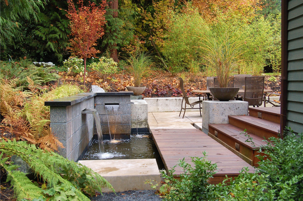 Large modern backyard partial sun formal garden in Seattle with a water feature and concrete pavers.