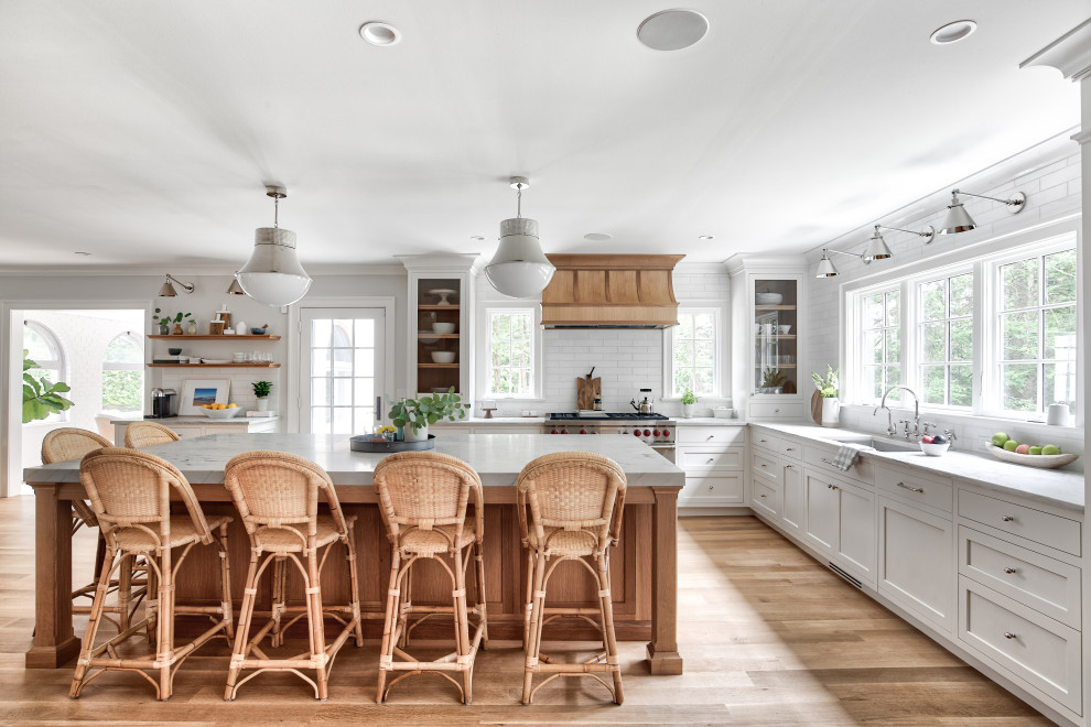 Inspiration for a large country l-shaped eat-in kitchen in New York with white splashback, light hardwood floors, with island, an undermount sink, shaker cabinets, white cabinets, stainless steel appliances, beige floor and white benchtop.