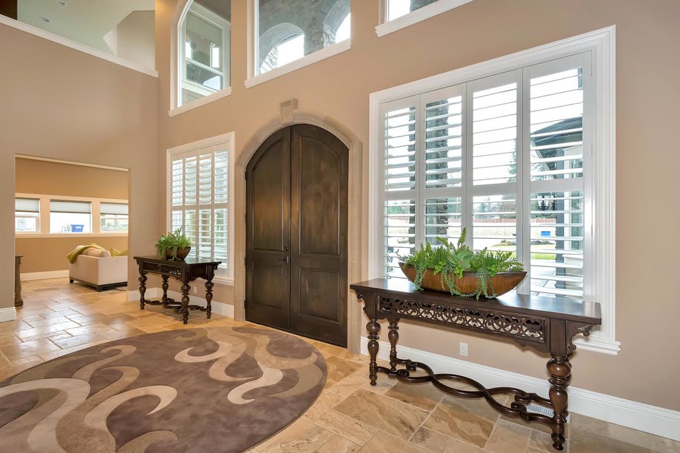 This is an example of a large transitional foyer in Seattle with beige walls, travertine floors, a double front door and a dark wood front door.
