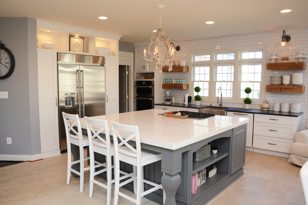 This is an example of a large transitional u-shaped eat-in kitchen in DC Metro with a farmhouse sink, white cabinets, quartz benchtops, white splashback, ceramic splashback, stainless steel appliances and with island.