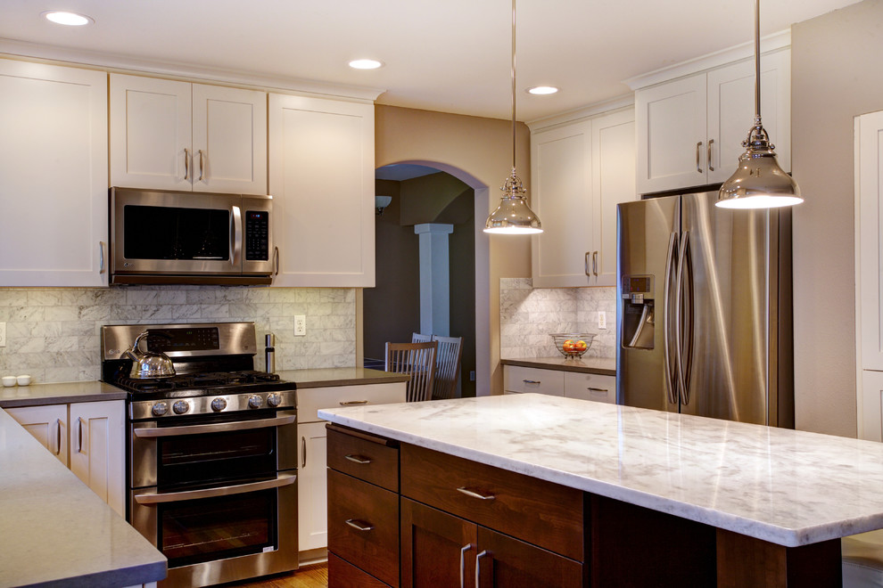 Inspiration for a mid-sized transitional l-shaped medium tone wood floor eat-in kitchen remodel in Seattle with an undermount sink, recessed-panel cabinets, white cabinets, quartz countertops, white backsplash, stone tile backsplash, stainless steel appliances and an island