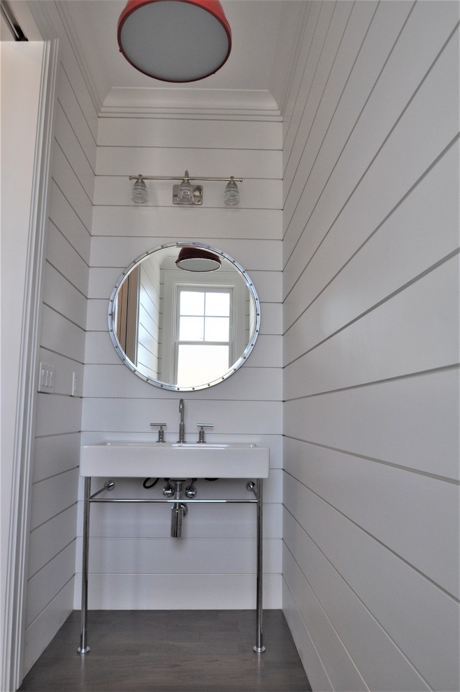 This is an example of a small beach style powder room in New York with open cabinets, white walls, medium hardwood floors, a pedestal sink and white benchtops.
